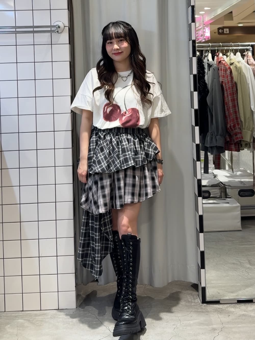 ブラック系のスカート、ブラック系のブーツ、ホワイト系のTシャツ/カットソーを着用したレディースの春コーディネートの2枚目の写真