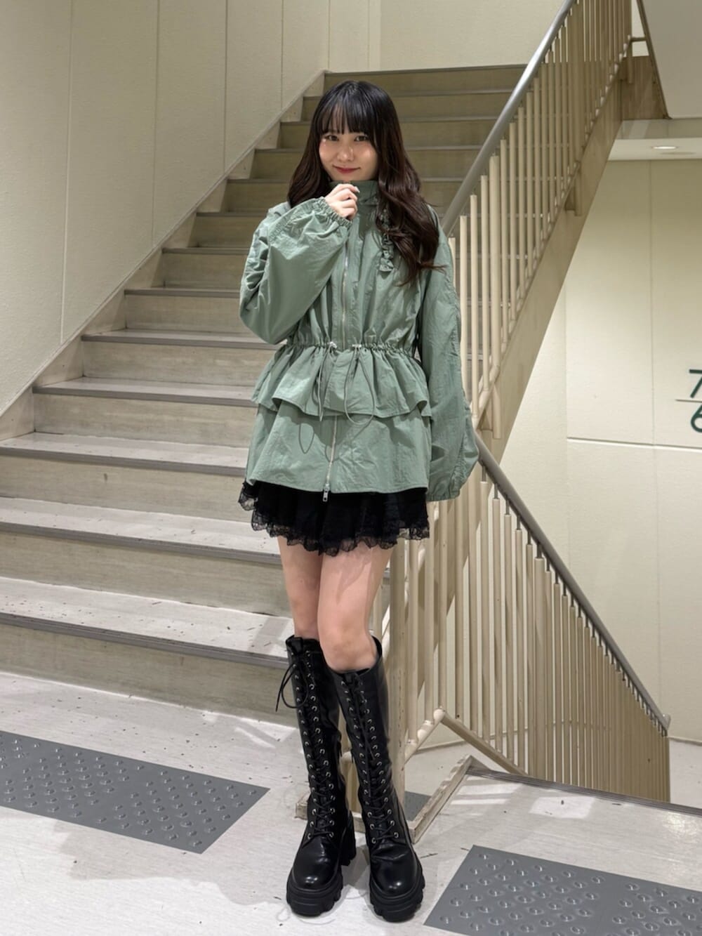 ブラック系のブーツ、グリーン系のナイロンジャケット、ブラック系のその他パンツを着用したレディースの春コーディネートの2枚目の写真