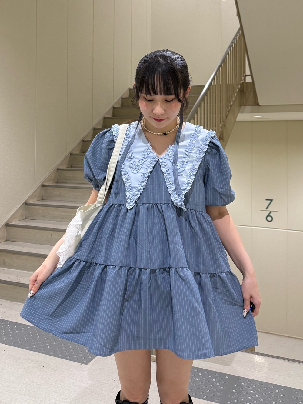 ブルー系のワンピース、ブラック系のブーツ、ホワイト系のトートバッグを着用したレディースの春コーディネートの7枚目の写真