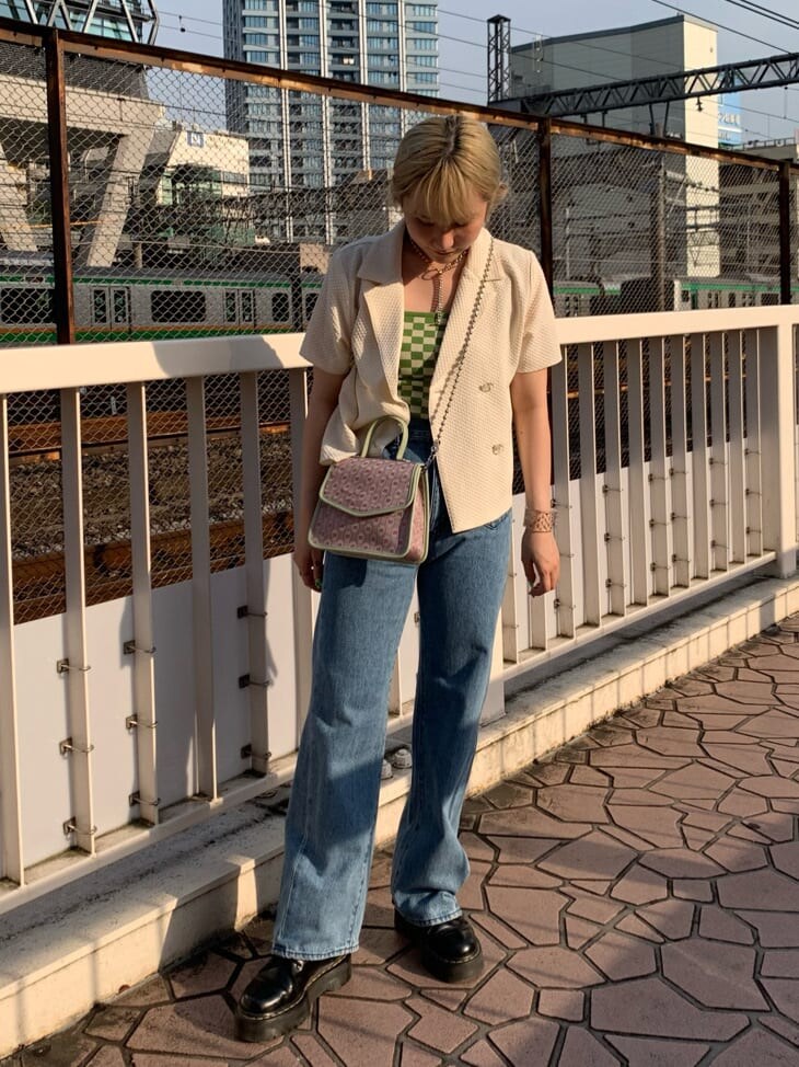 グリーン系のキャミソール、ピンク系のハンドバッグ、ブルー系のデニムパンツを着用したレディースの夏コーディネートの2枚目の写真