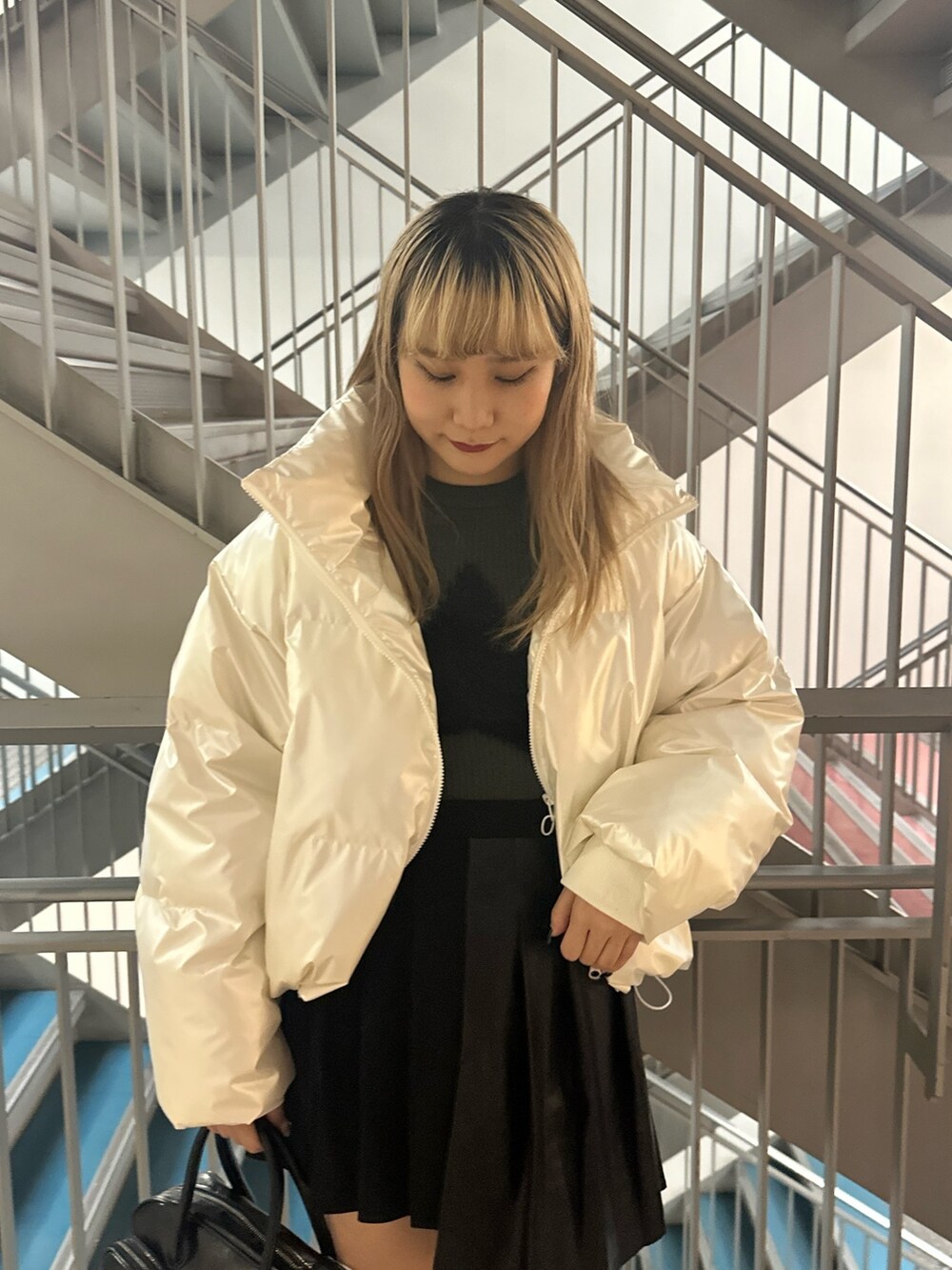 ブラック系のボストンバッグ、ホワイト系のダウンジャケット/コート、グリーン系のニット/セーターを着用したレディースの冬コーディネートの4枚目の写真