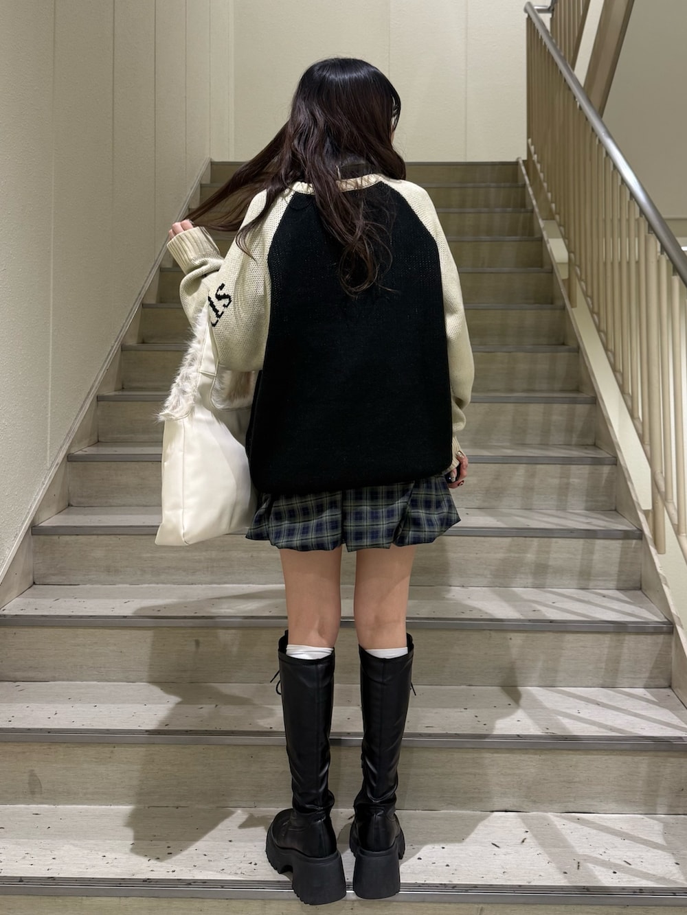 ブラック系のニット/セーター、グリーン系のワンピース、ホワイト系のハンドバッグを着用したレディースの冬コーディネートの3枚目の写真