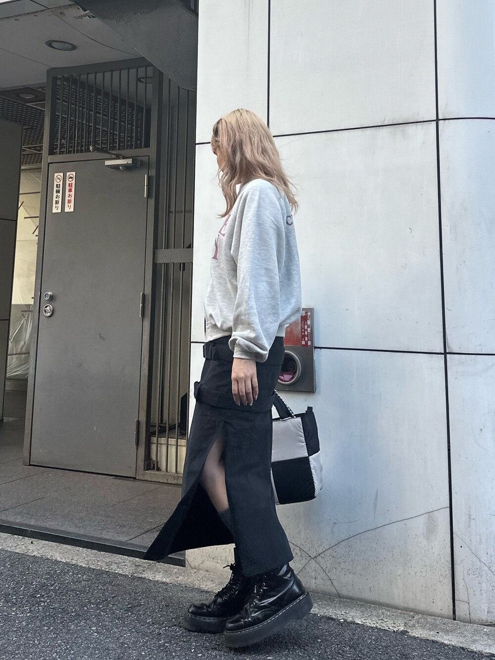 グレー系のスウェット、ブラック系のスカート、ブラック系のハンドバッグを着用したレディースの秋コーディネートの2枚目の写真