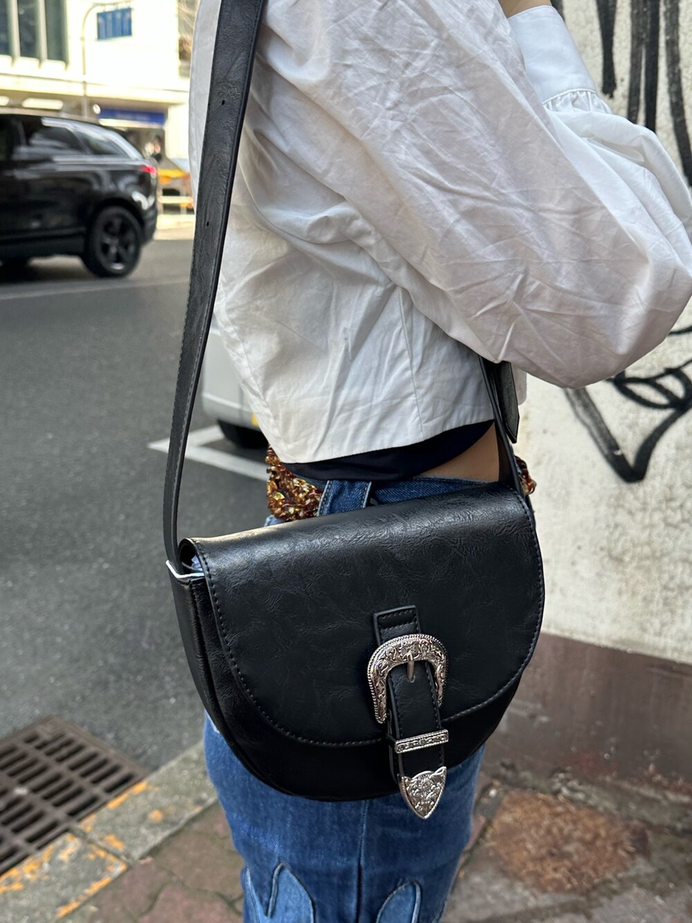 ホワイト系のシャツ/ブラウス、ブルー系のデニムパンツ、ブラック系のショルダーバッグを着用したレディースの春コーディネートの8枚目の写真