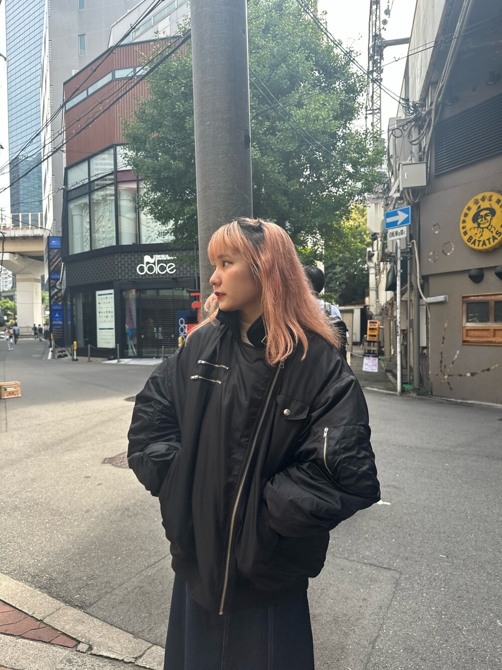 ブルー系のジャンパースカート、ホワイト系のニット/セーター、ブラック系のMA-1を着用したレディースの夏コーディネートの3枚目の写真