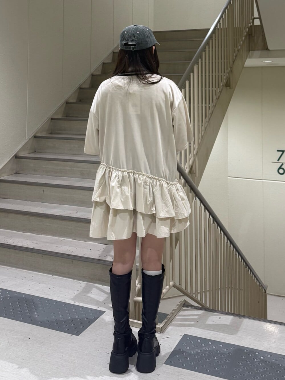 ブラック系のブーツ、ホワイト系のワンピース、ホワイト系のTシャツ/カットソーを着用したレディースの春コーディネートの4枚目の写真