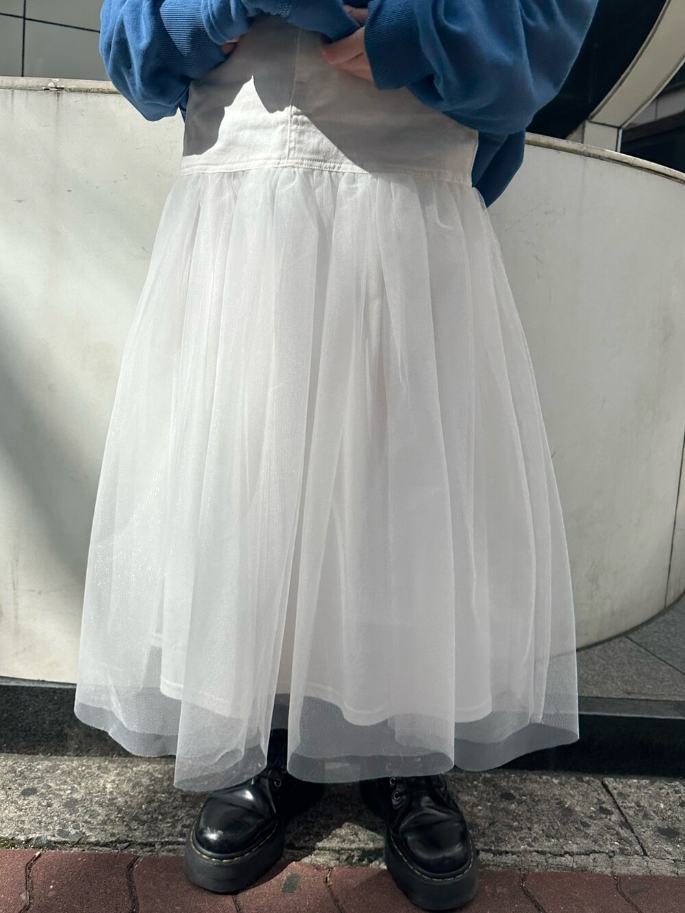 ブルー系のパーカー、ホワイト系のスカート、ブラック系のブーツを着用したレディースの春コーディネートの6枚目の写真