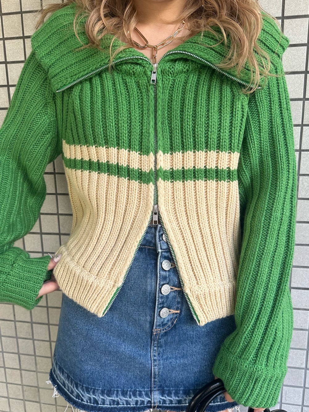 グリーン系のニット/セーター、ブルー系のデニムパンツ、ブラウン系のブーツを着用したレディースの秋コーディネートの6枚目の写真