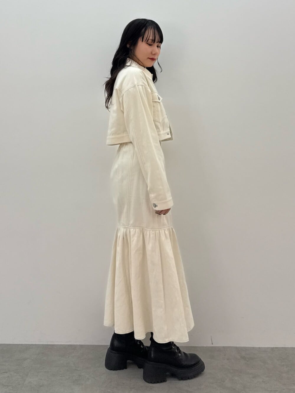 ブラック系のブーツ、ホワイト系のワンピース、ブルー系のTシャツ/カットソーを着用したレディースの春コーディネートの3枚目の写真