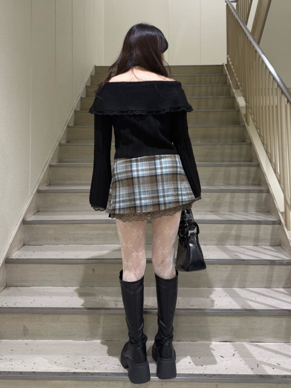 ブラック系のブーツ、ブラウン系のスカート、ブラック系のハンドバッグを着用したレディースの冬コーディネートの4枚目の写真