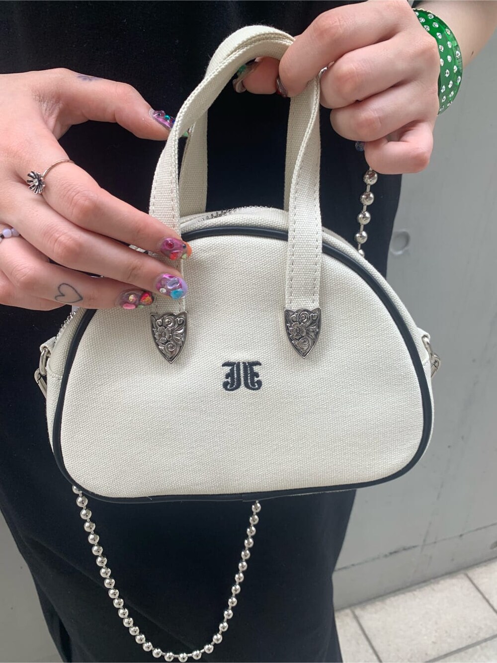 ホワイト系のボストンバッグ、ブラック系のワンピース、グリーン系のバングル/リストバンドを着用したレディースの春コーディネートの8枚目の写真