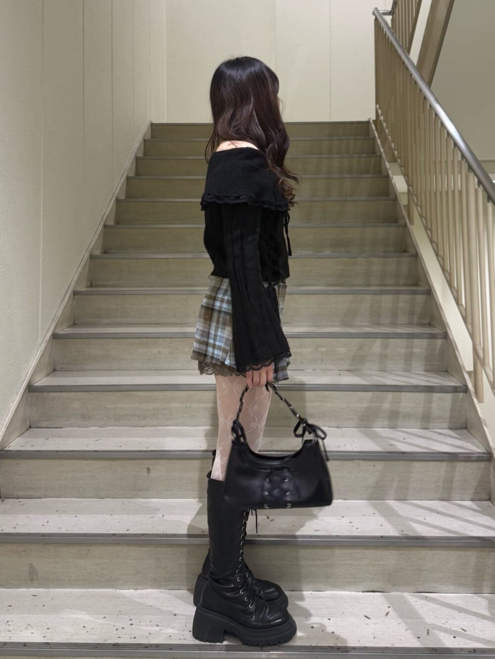 ブラック系のブーツ、ブラウン系のスカート、ブラック系のハンドバッグを着用したレディースの冬コーディネートの3枚目の写真