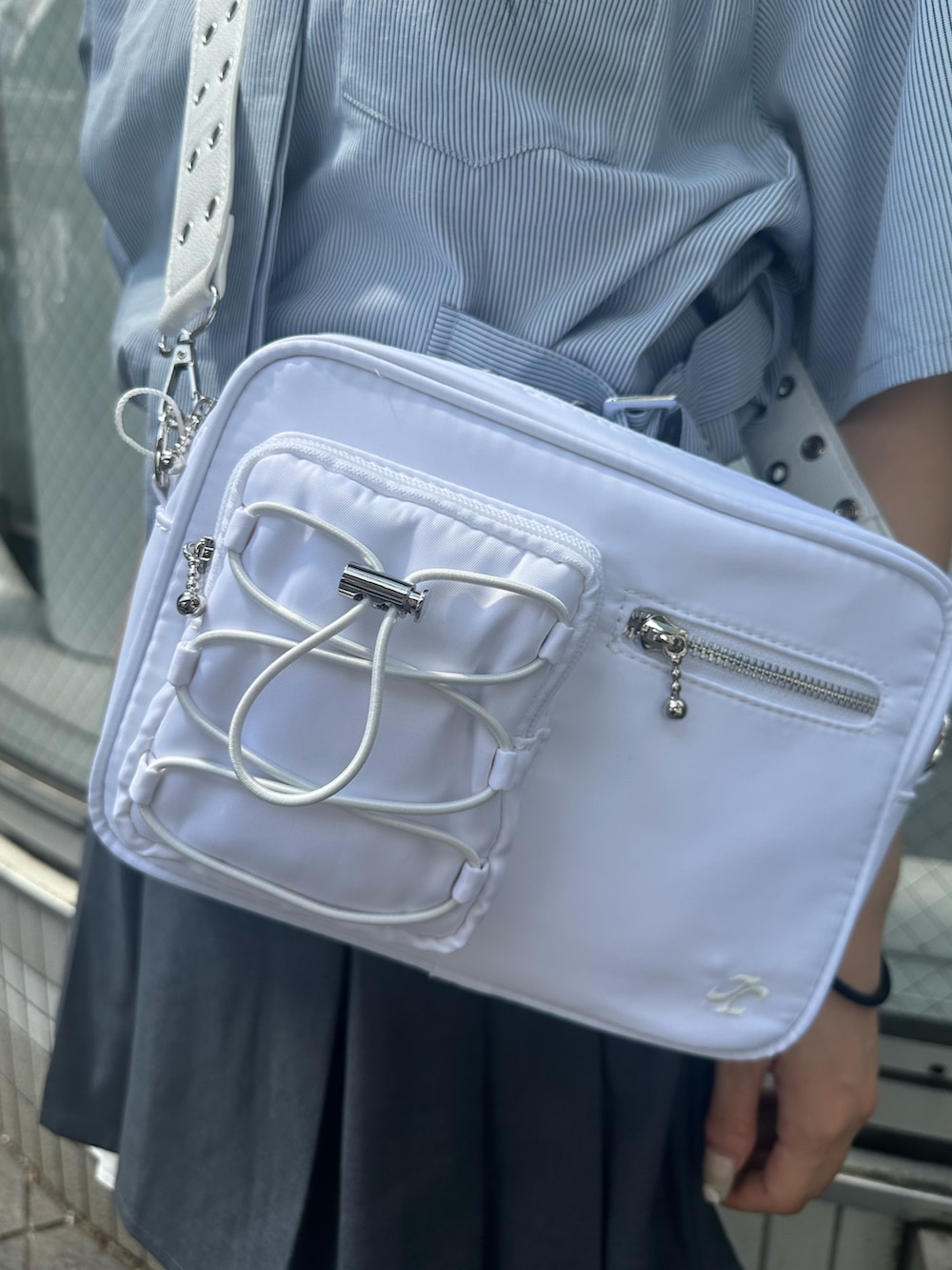 グレー系のスカート、ホワイト系のショルダーバッグ、ブルー系のシャツ/ブラウスを着用したレディースの夏コーディネートの6枚目の写真