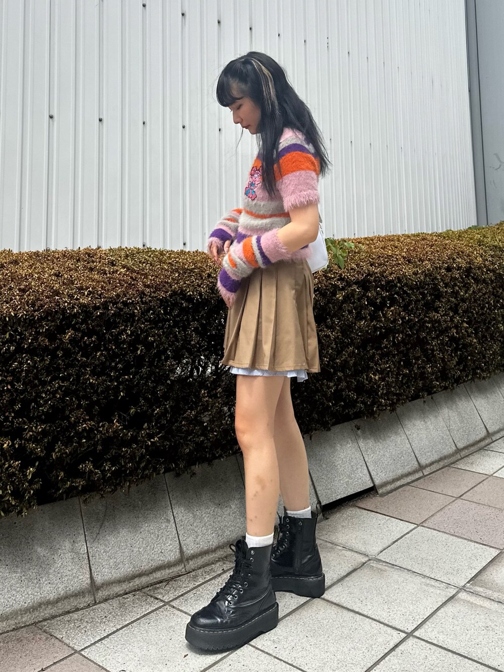 ピンク系のニット/セーター、ベージュ系のスカート、ホワイト系のショルダーバッグを着用したレディースの夏コーディネートの3枚目の写真