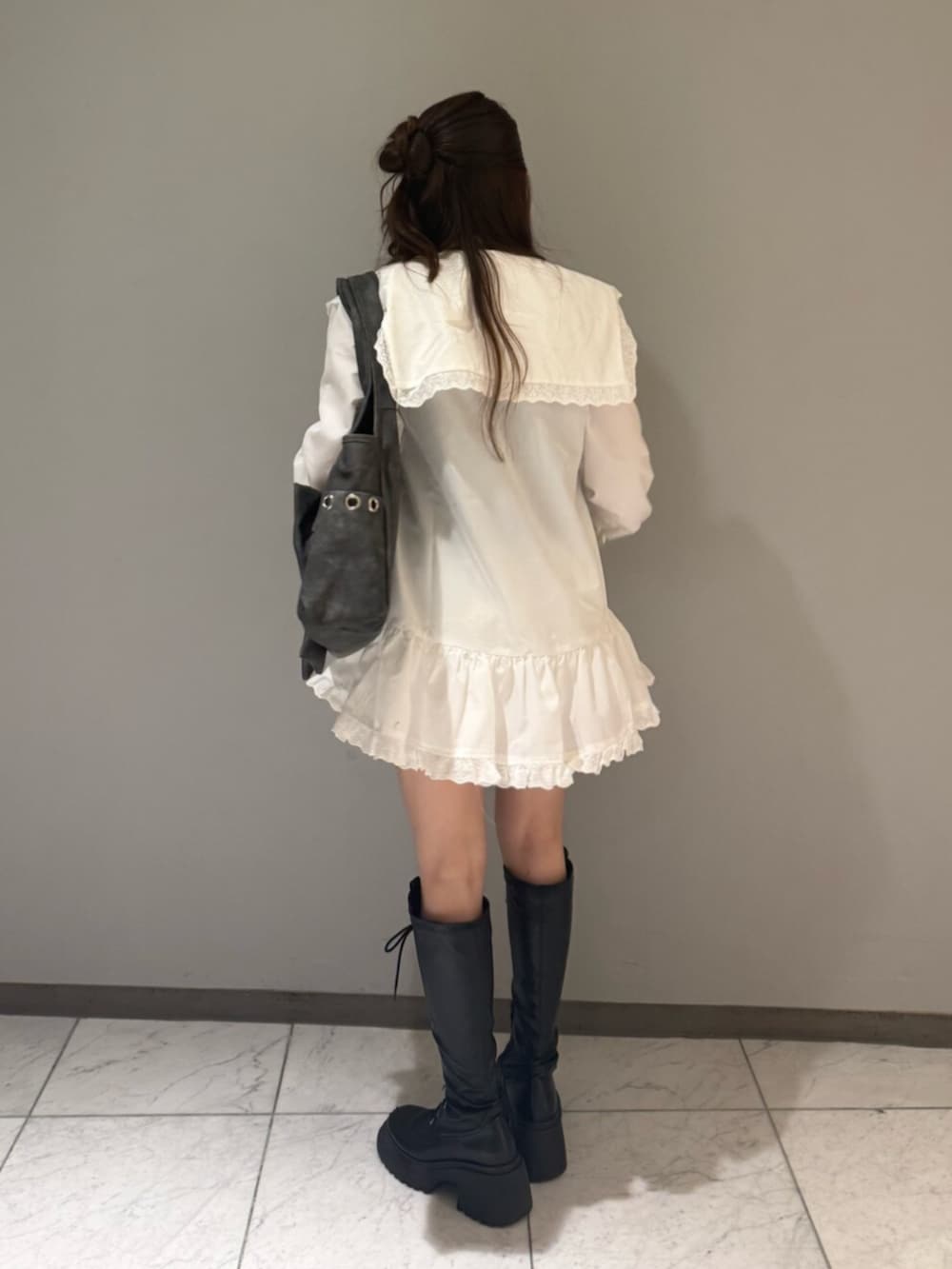 グレー系のトートバッグ、ブラック系のブーツ、ホワイト系のワンピースを着用したレディースの夏コーディネートの3枚目の写真