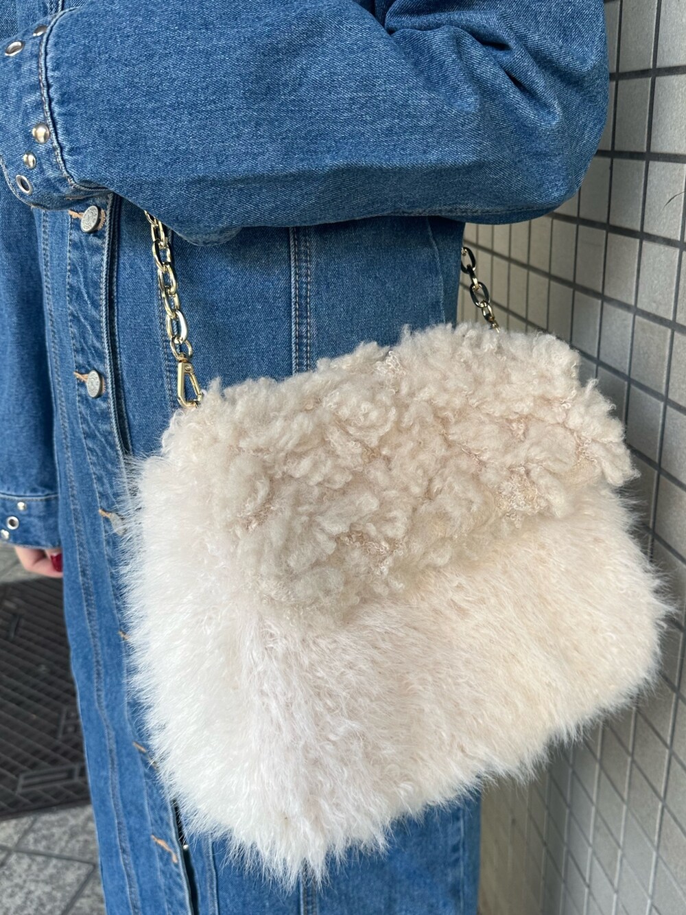 ブルー系のワンピース、ホワイト系のハンドバッグ、ブラック系のブーツを着用したレディースの冬コーディネートの7枚目の写真