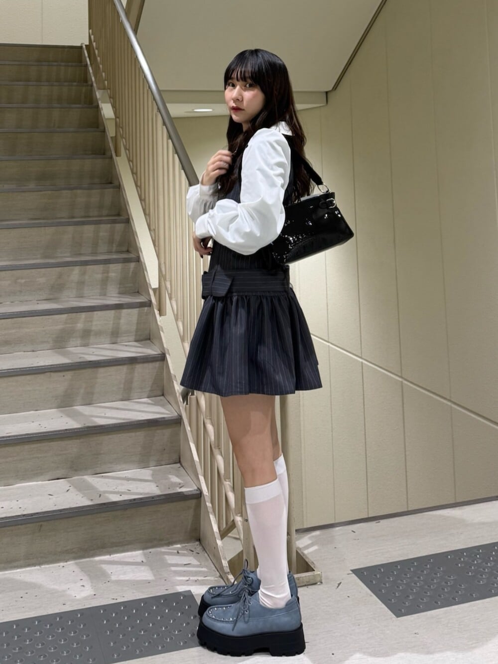 ブラック系のハンドバッグ、グレー系のシャツワンピース、ブルー系のローファーを着用したレディースの冬コーディネートの3枚目の写真