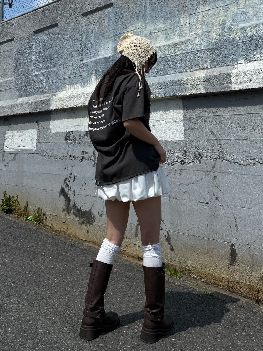 ブラウン系のブーツ、ブラック系のTシャツ/カットソー、ホワイト系のスカートを着用したレディースの春コーディネートの2枚目の写真