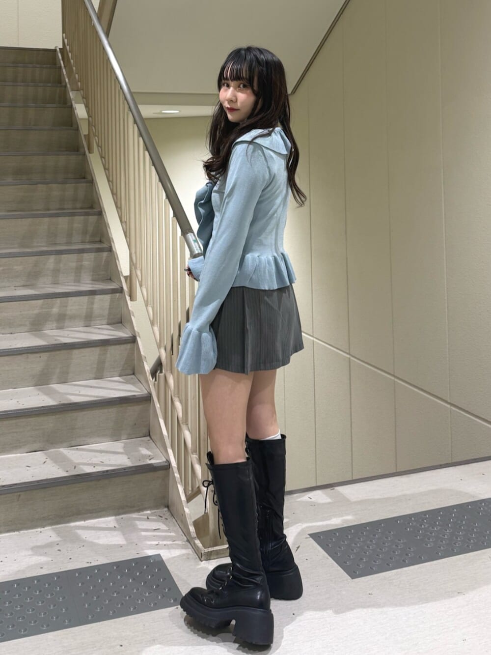 ブラック系のブーツ、グレー系のスカート、ブルー系のニット/セーターを着用したレディースの冬コーディネートの2枚目の写真