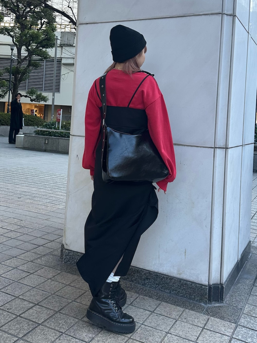 ブラック系のワンピース、ブラック系のショルダーバッグ、レッド系のスウェットを着用したレディースの冬コーディネートの3枚目の写真
