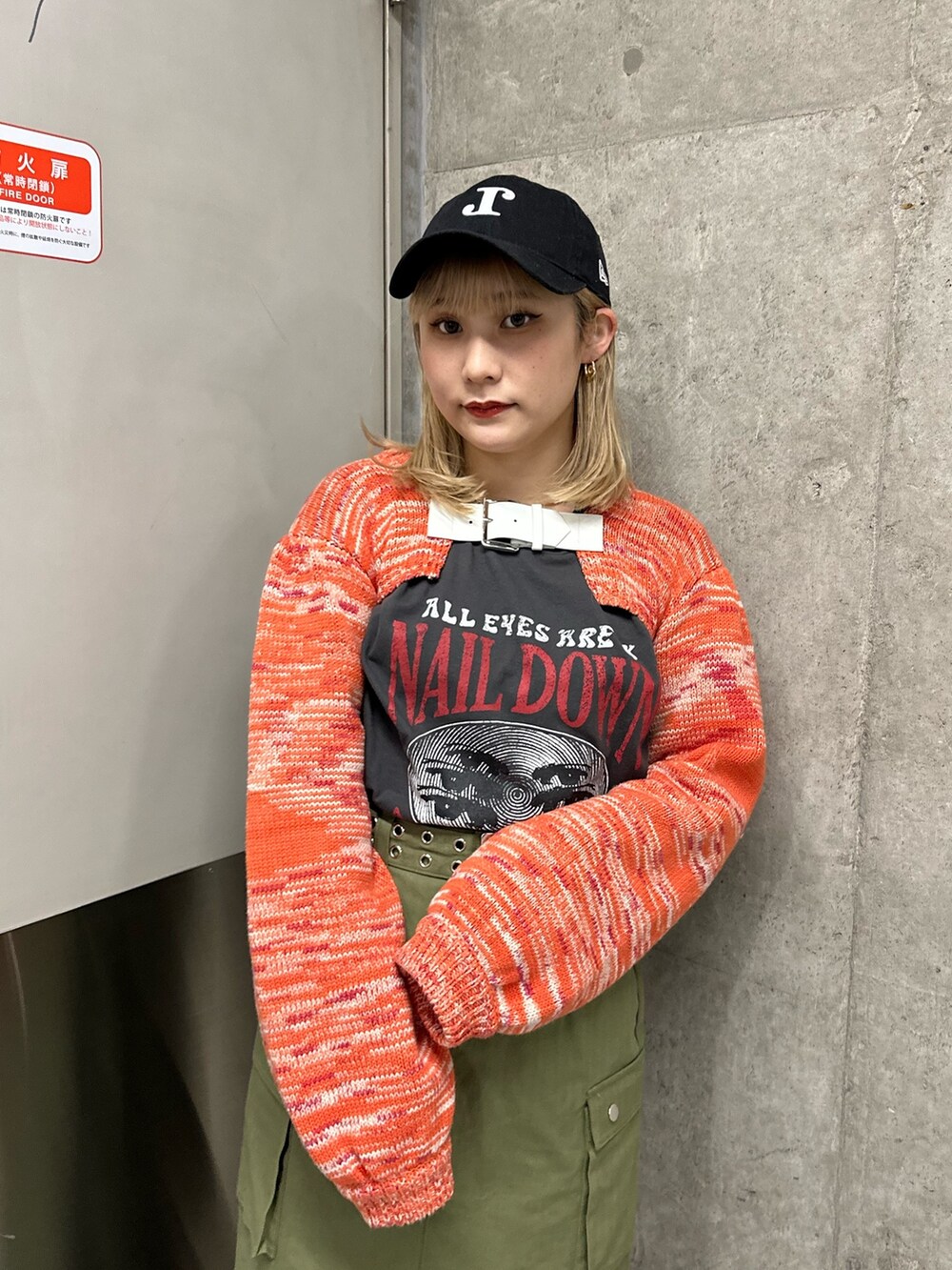 オレンジ系のニット/セーター、ブラック系のTシャツ/カットソー、ベージュ系のスカートを着用したレディースの冬コーディネートの4枚目の写真