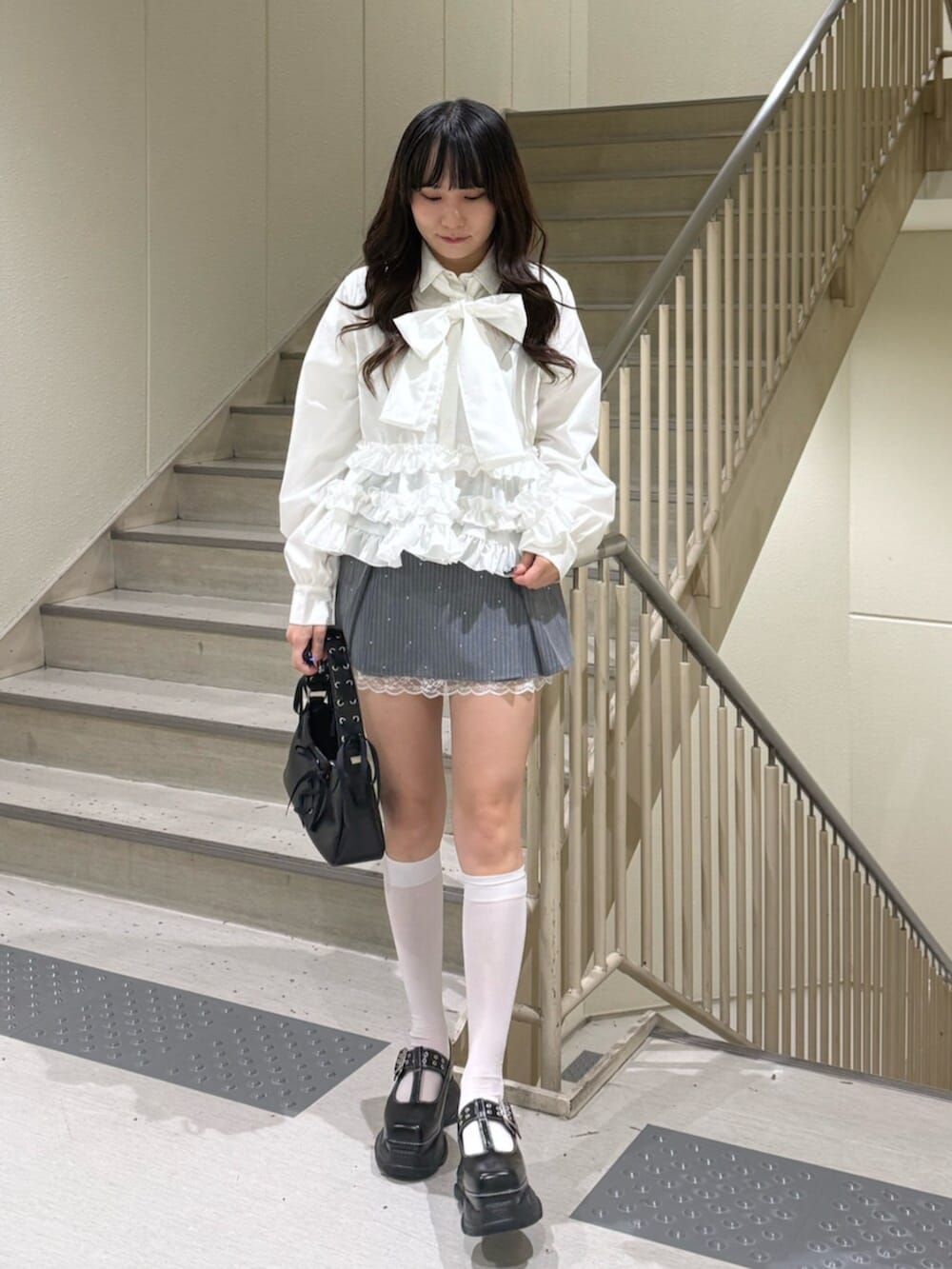 ブラック系のハンドバッグ、ブラック系のローファー、グレー系のスカートを着用したレディースの冬コーディネートの5枚目の写真