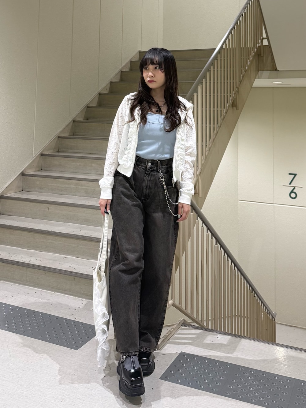 ホワイト系のパーカー、ブラック系のデニムパンツ、ホワイト系のトートバッグを着用したレディースの春コーディネートの6枚目の写真