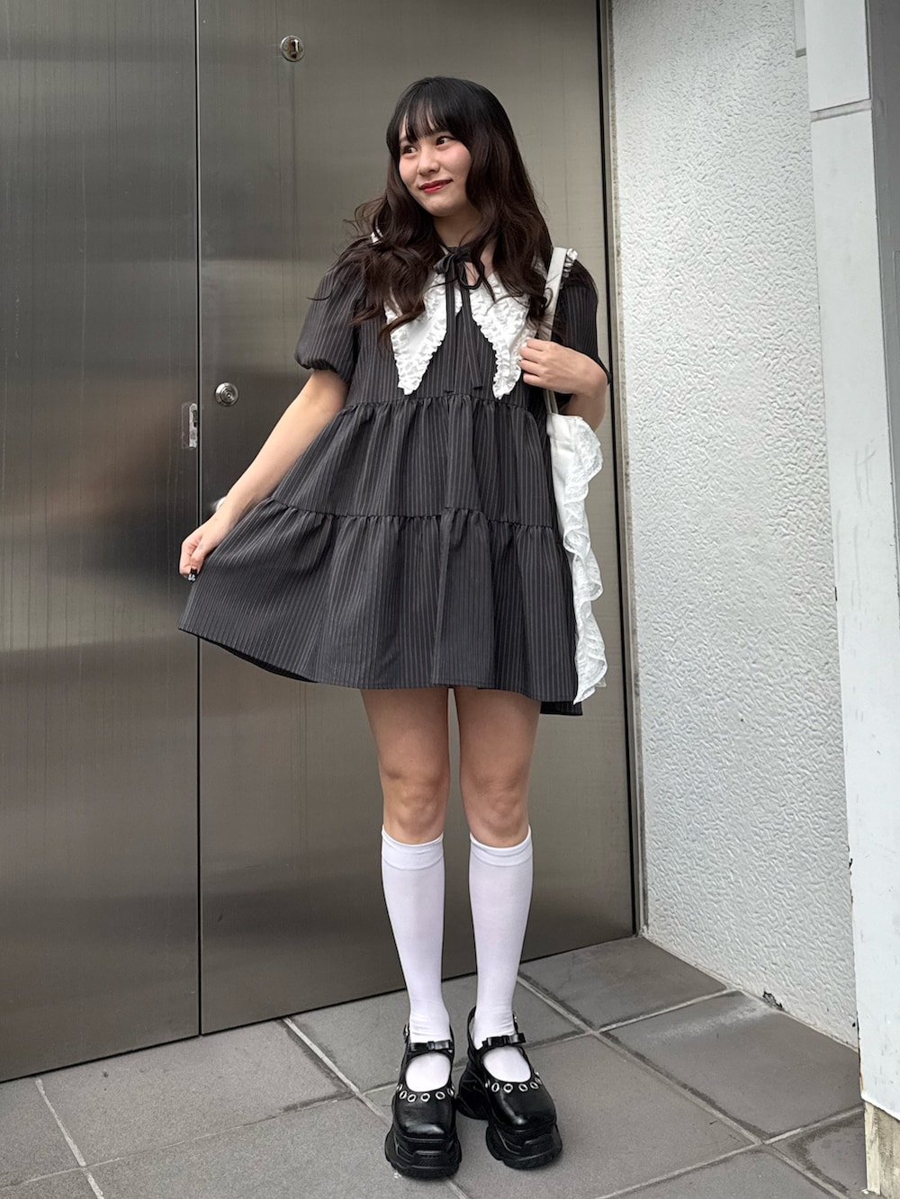 グレー系のワンピース、ホワイト系のトートバッグを着用したレディースの冬コーディネートの2枚目の写真