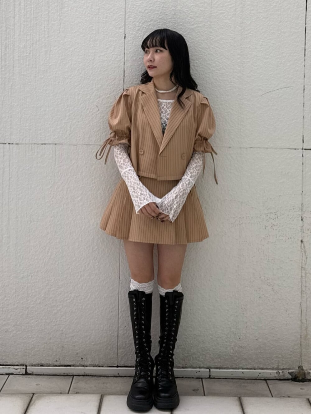 ブラック系のブーツ、ホワイト系のTシャツ/カットソー、ベージュ系のテーラードジャケットを着用したレディースの冬コーディネートの2枚目の写真