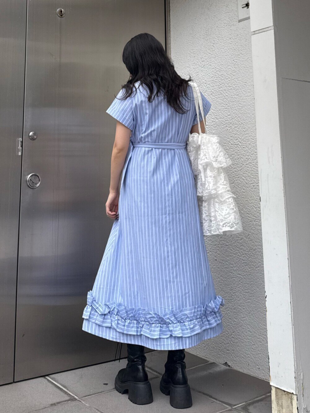 ブラック系のブーツ、ブルー系のワンピース、ホワイト系のトートバッグを着用したレディースの春コーディネートの4枚目の写真