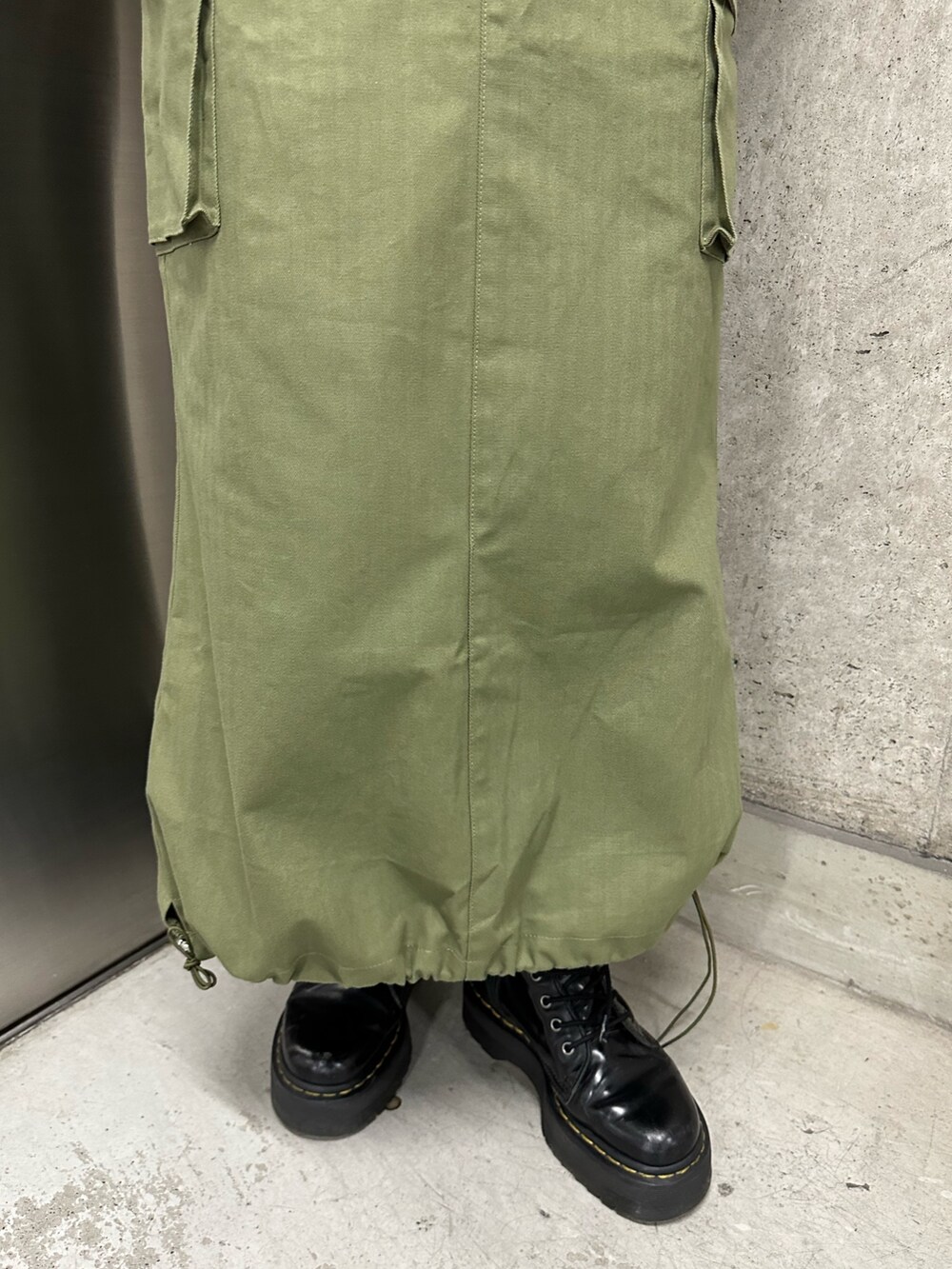 オレンジ系のニット/セーター、ブラック系のTシャツ/カットソー、ベージュ系のスカートを着用したレディースの冬コーディネートの8枚目の写真