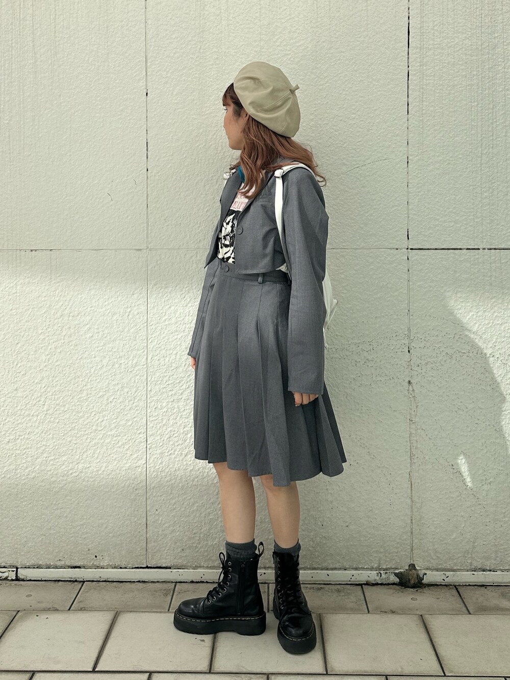 グレー系のスカート、ホワイト系のTシャツ/カットソー、ホワイト系のバックパック/リュックを着用したレディースの冬コーディネートの3枚目の写真