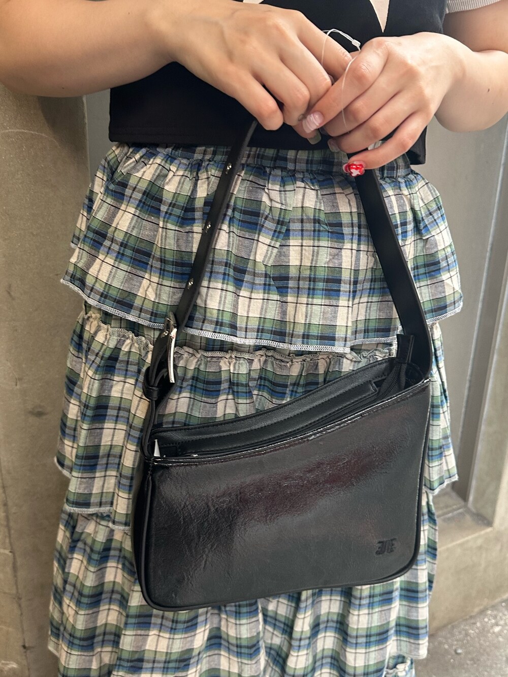 ブラック系のハンドバッグ、ブラック系のTシャツ/カットソー、グリーン系のスカートを着用したレディースの夏コーディネートの8枚目の写真