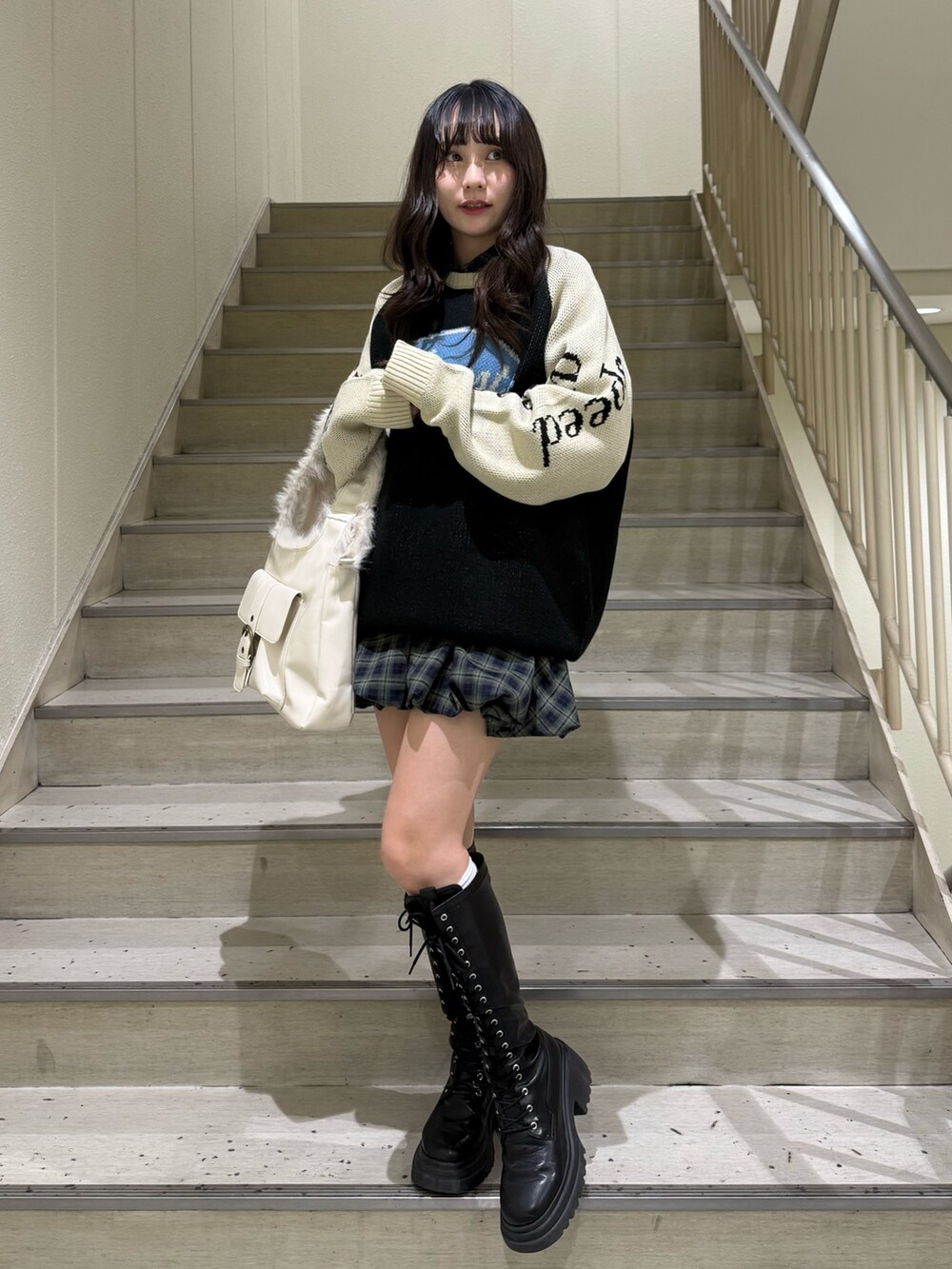 ブラック系のニット/セーター、グリーン系のワンピース、ホワイト系のハンドバッグを着用したレディースの冬コーディネートの5枚目の写真