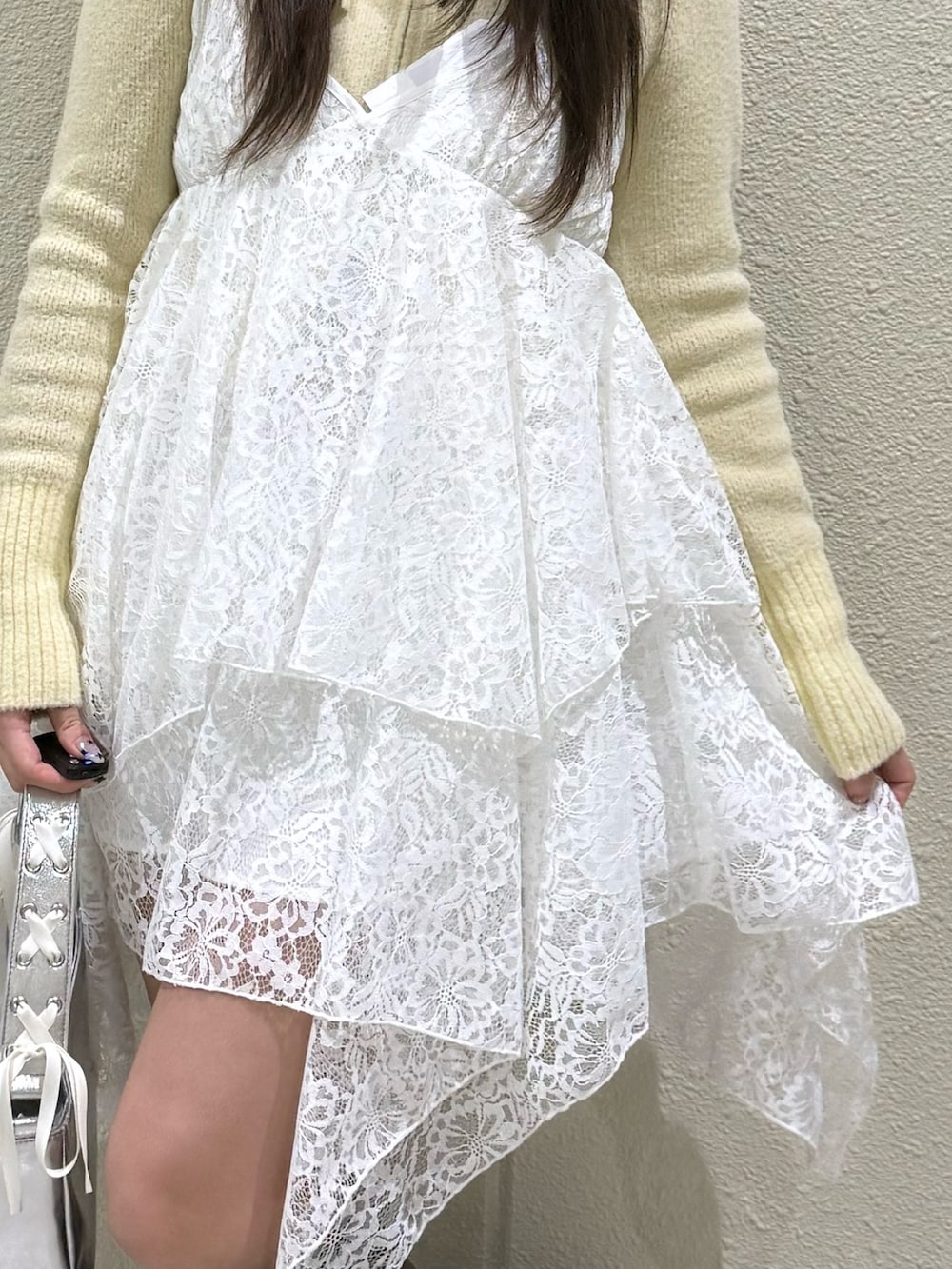 イエロー系のパーカー、ホワイト系のワンピース、シルバー系のハンドバッグを着用したレディースの冬コーディネートの7枚目の写真