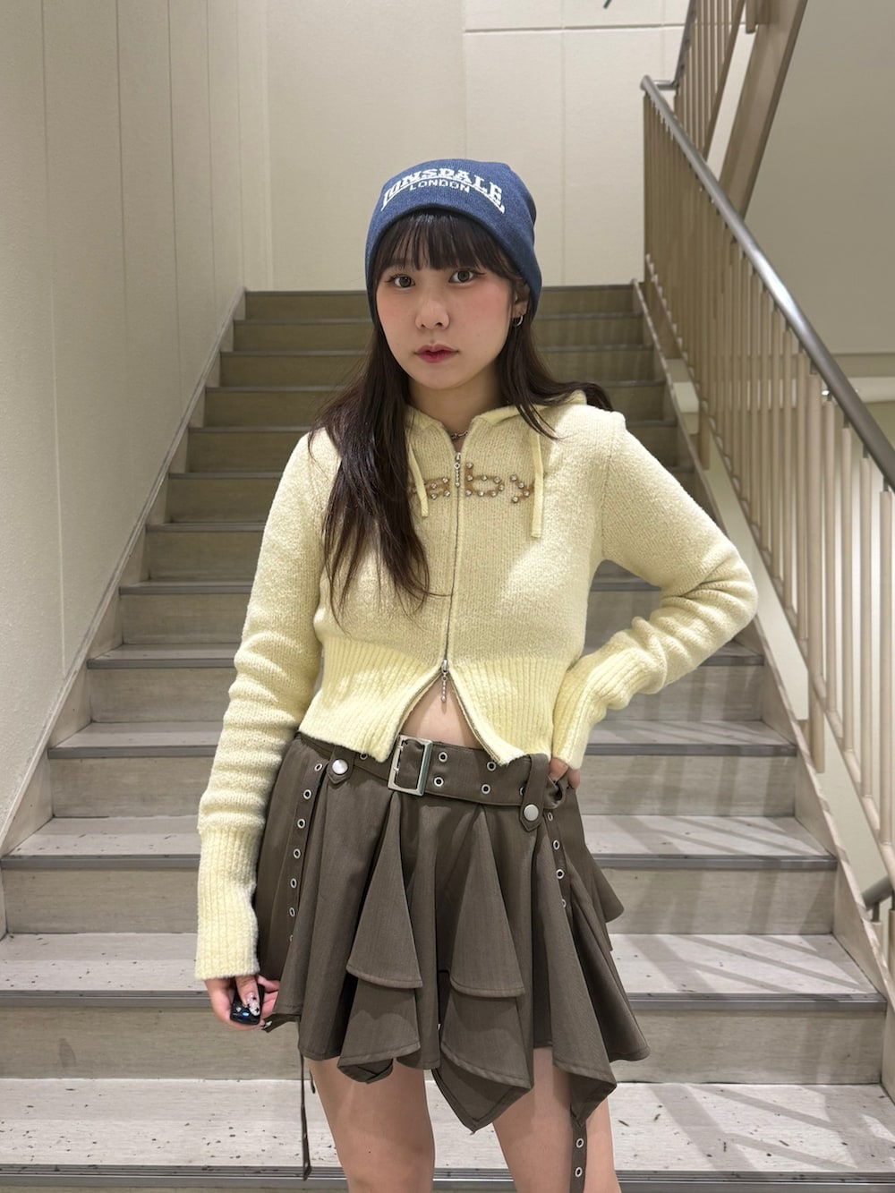 イエロー系のパーカー、ベージュ系のスカート、ブラック系のブーツを着用したレディースの冬コーディネートの7枚目の写真