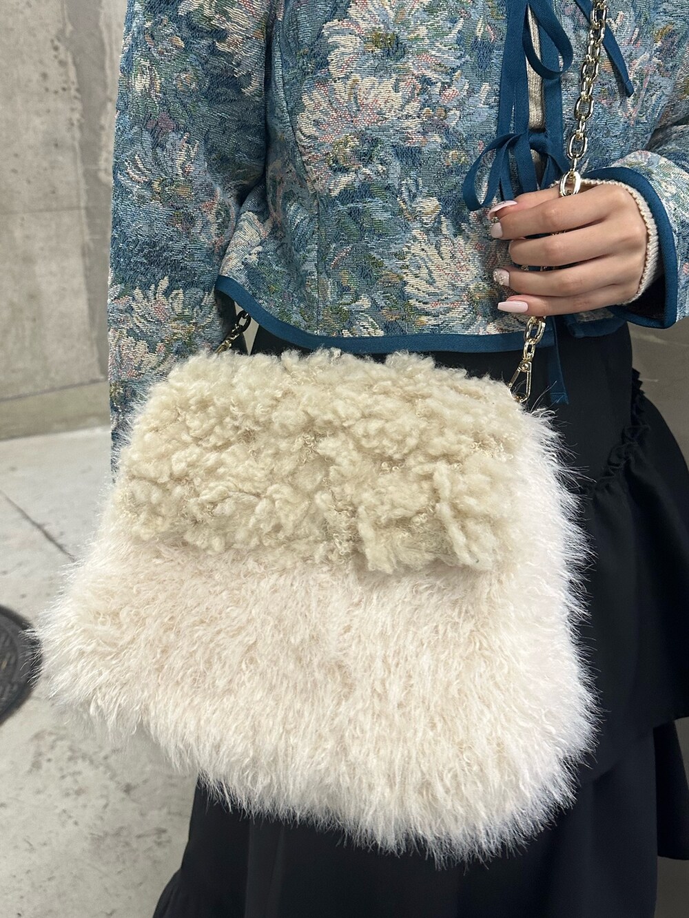 ブラック系のスカート、ブルー系のノーカラージャケット、ホワイト系のハンドバッグを着用したレディースの冬コーディネートの7枚目の写真