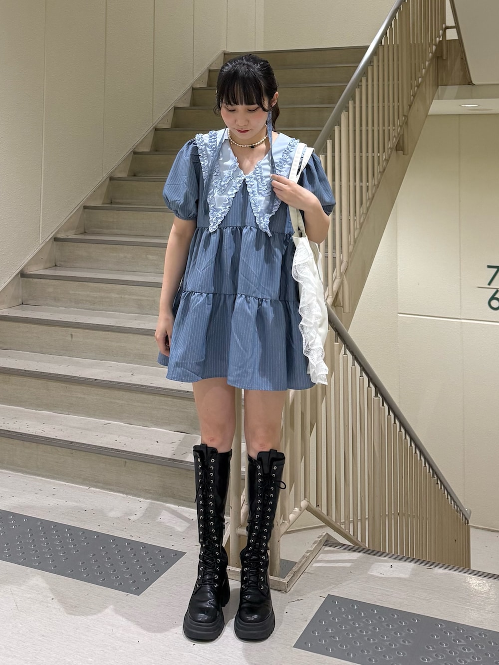 ブルー系のワンピース、ブラック系のブーツ、ホワイト系のトートバッグを着用したレディースの春コーディネートの5枚目の写真