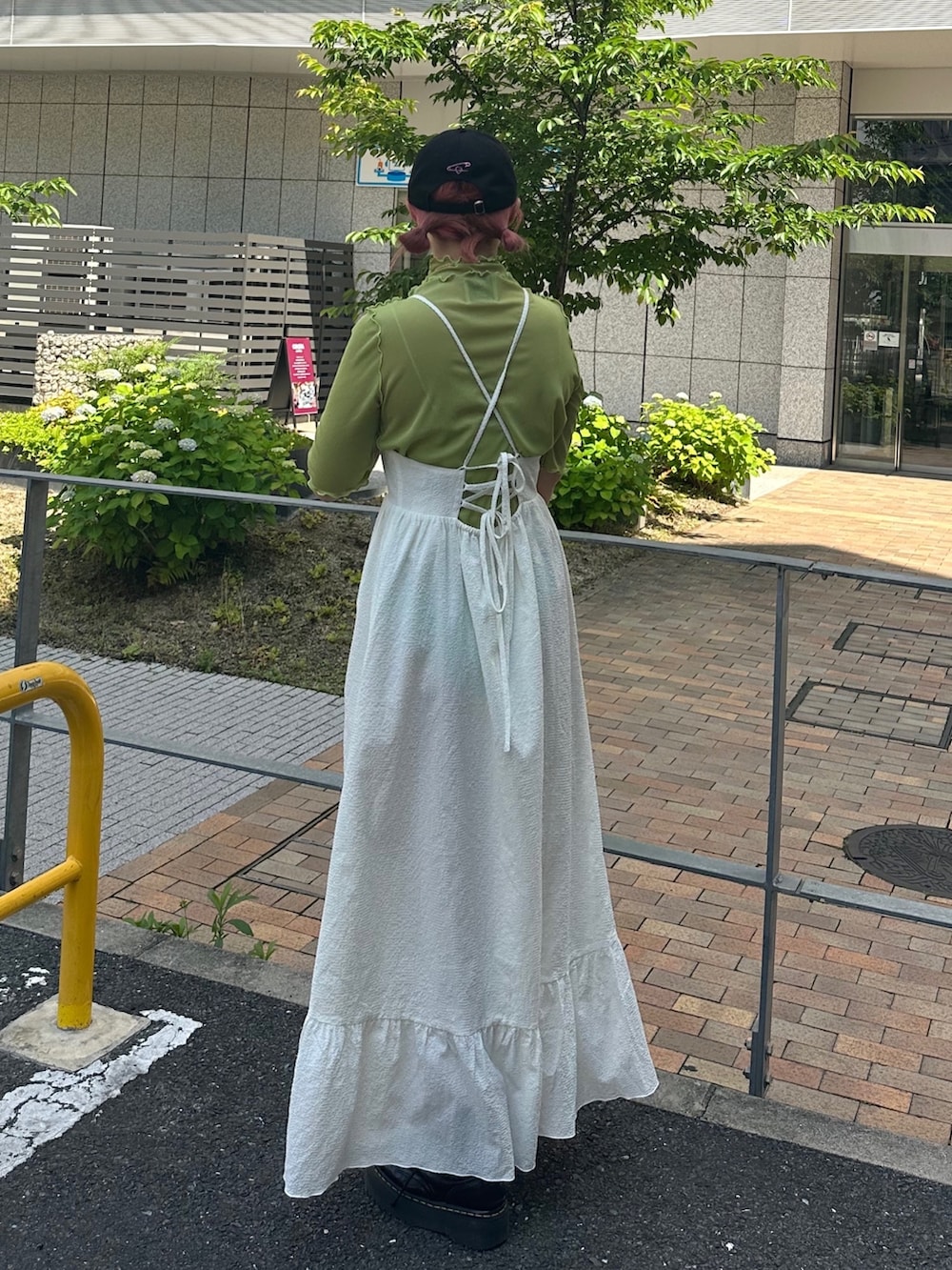 シルバー系のハンドバッグ、ブラック系のブーツ、ホワイト系のワンピースを着用したレディースの春コーディネートの3枚目の写真