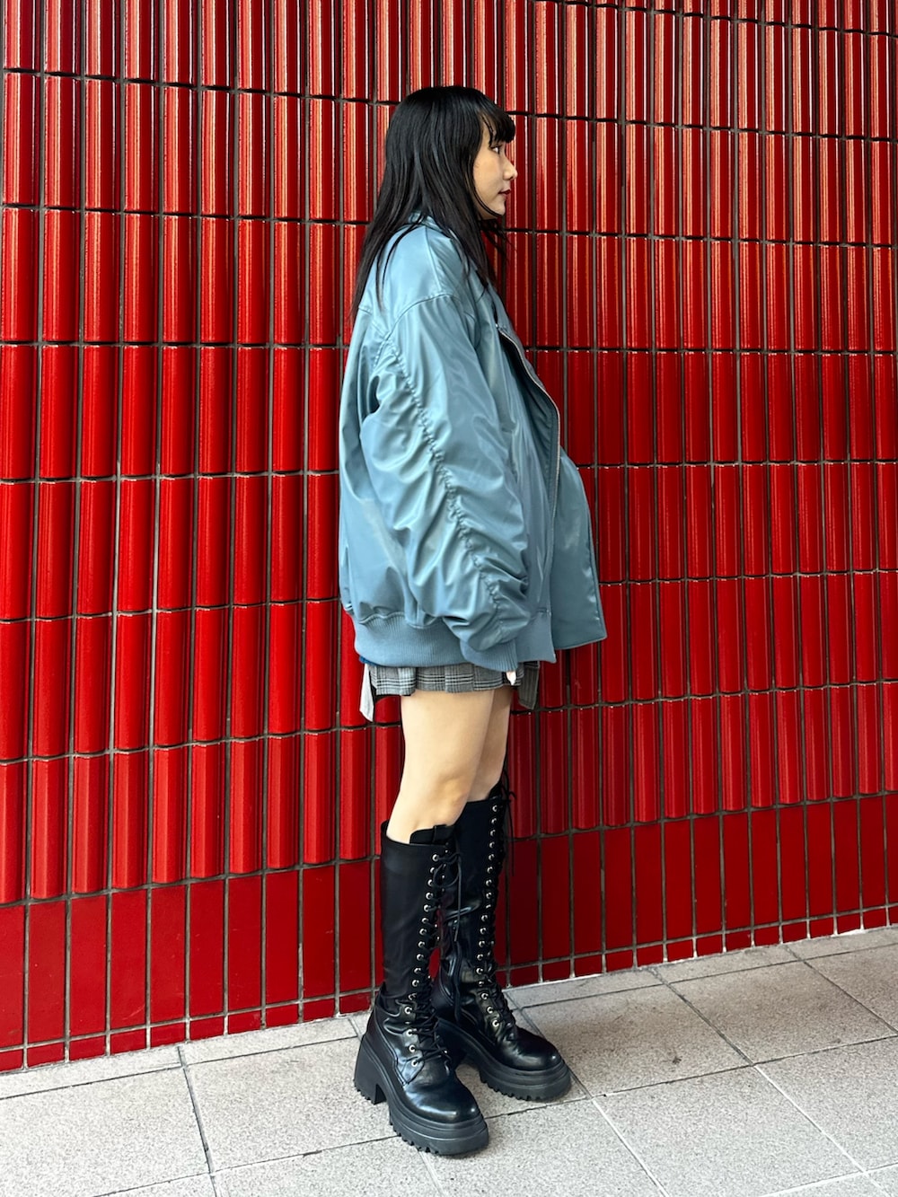 グレー系のスカート、ブラック系のブーツ、ブルー系のブルゾンを着用したレディースの秋コーディネートの3枚目の写真