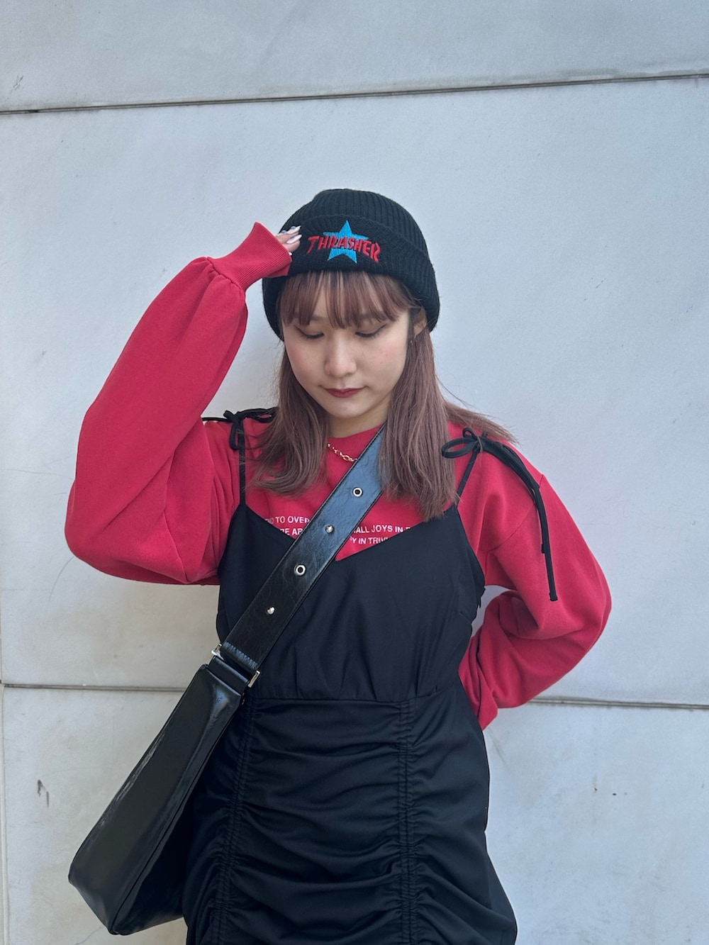 ブラック系のワンピース、ブラック系のショルダーバッグ、レッド系のスウェットを着用したレディースの冬コーディネートの5枚目の写真