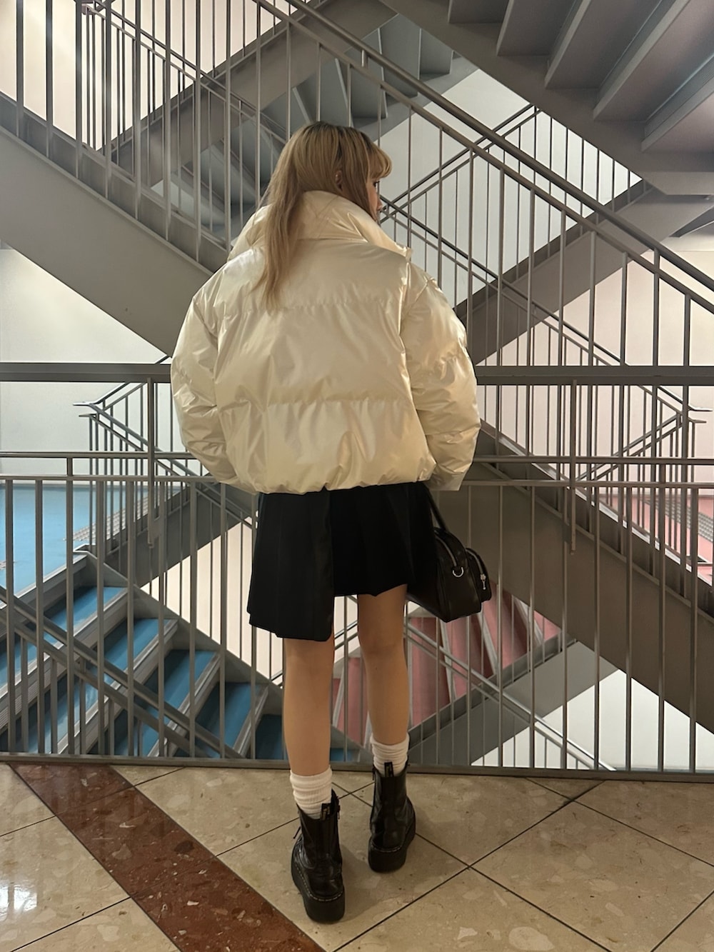 ブラック系のボストンバッグ、ホワイト系のダウンジャケット/コート、グリーン系のニット/セーターを着用したレディースの冬コーディネートの2枚目の写真