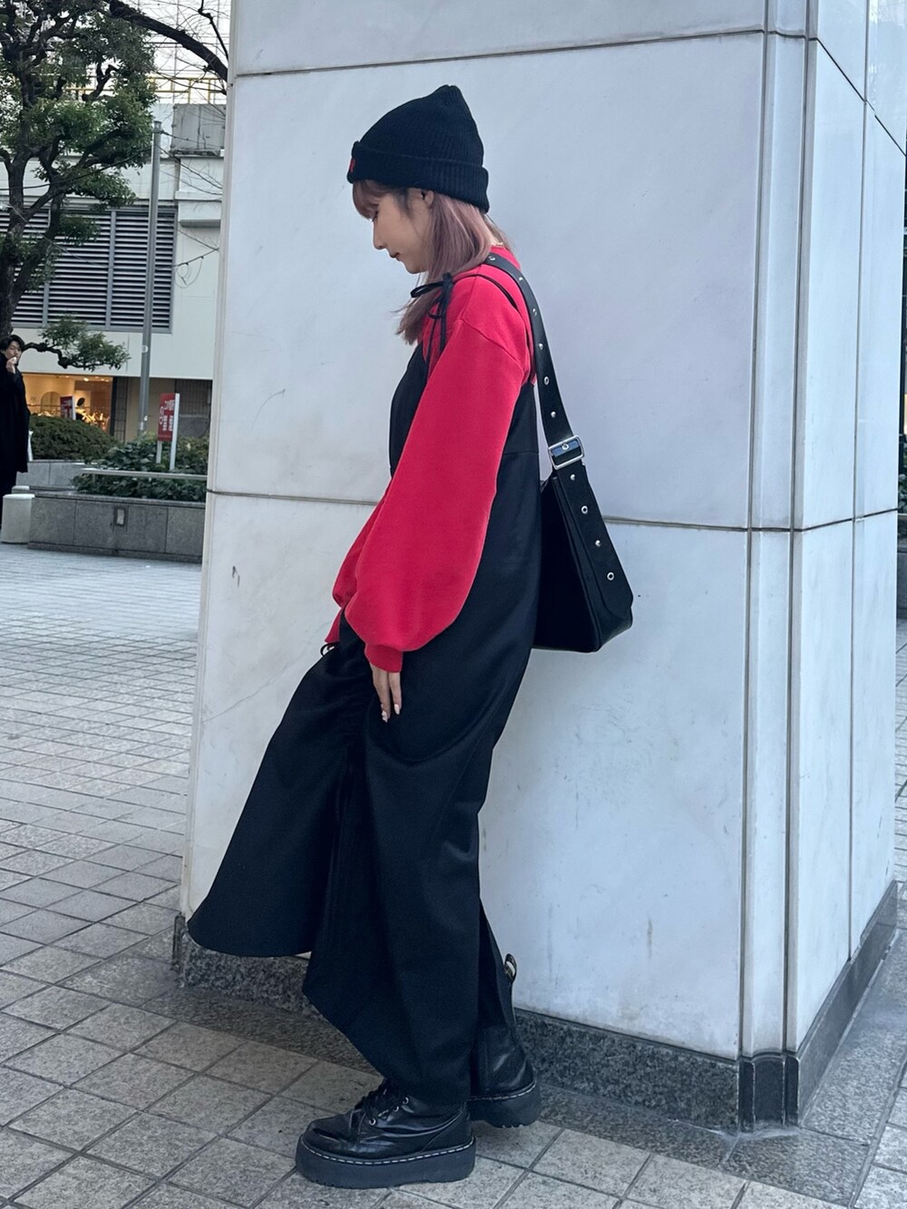 ブラック系のワンピース、ブラック系のショルダーバッグ、レッド系のスウェットを着用したレディースの冬コーディネートの4枚目の写真