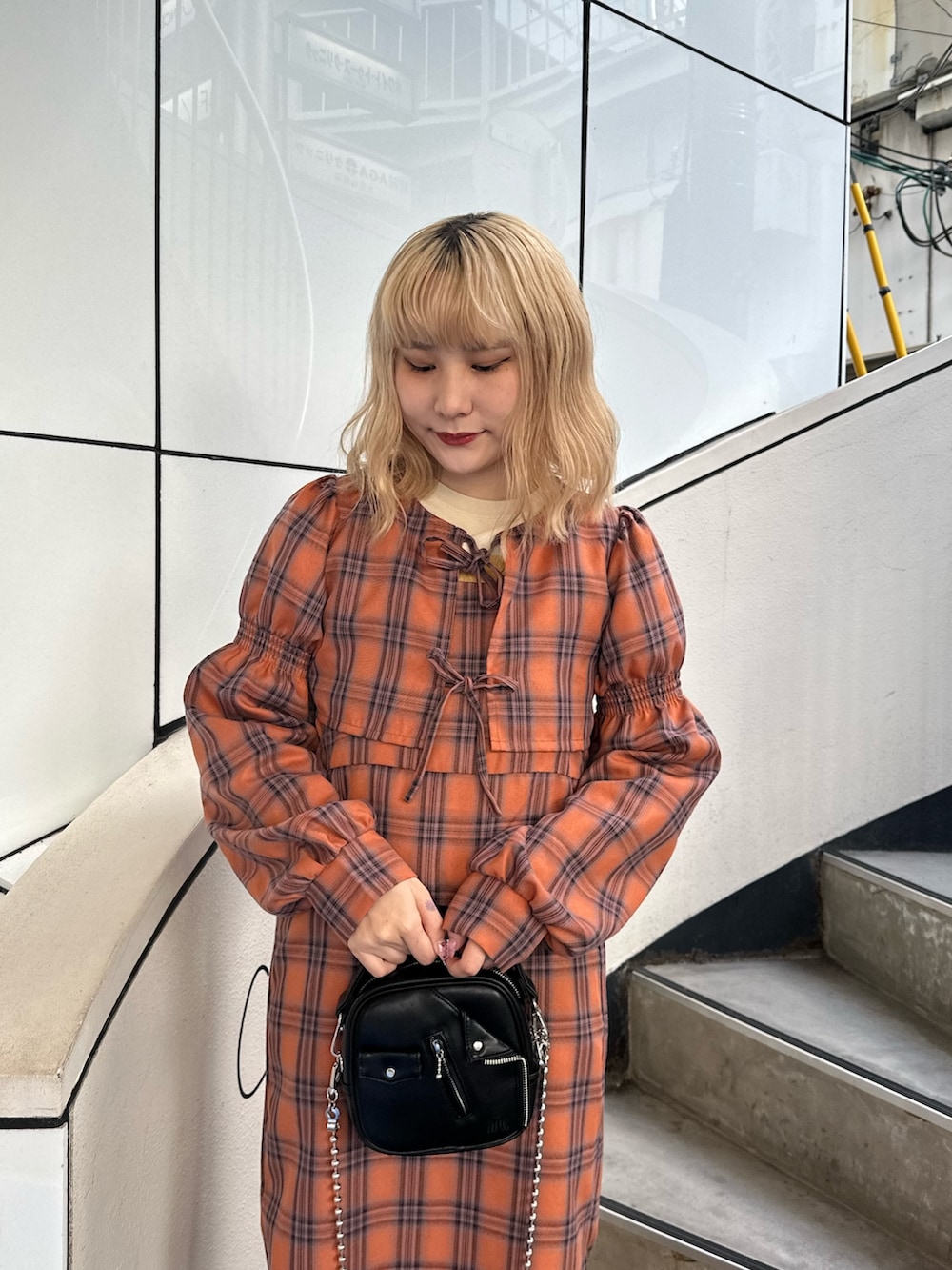 オレンジ系のワンピース、ホワイト系のハンドバッグ、ホワイト系のTシャツ/カットソーを着用したレディースの秋コーディネートの3枚目の写真