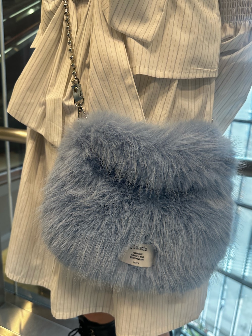 ホワイト系のシャツワンピース、ブルー系のハンドバッグ、ブラック系のブーツを着用したレディースの夏コーディネートの7枚目の写真