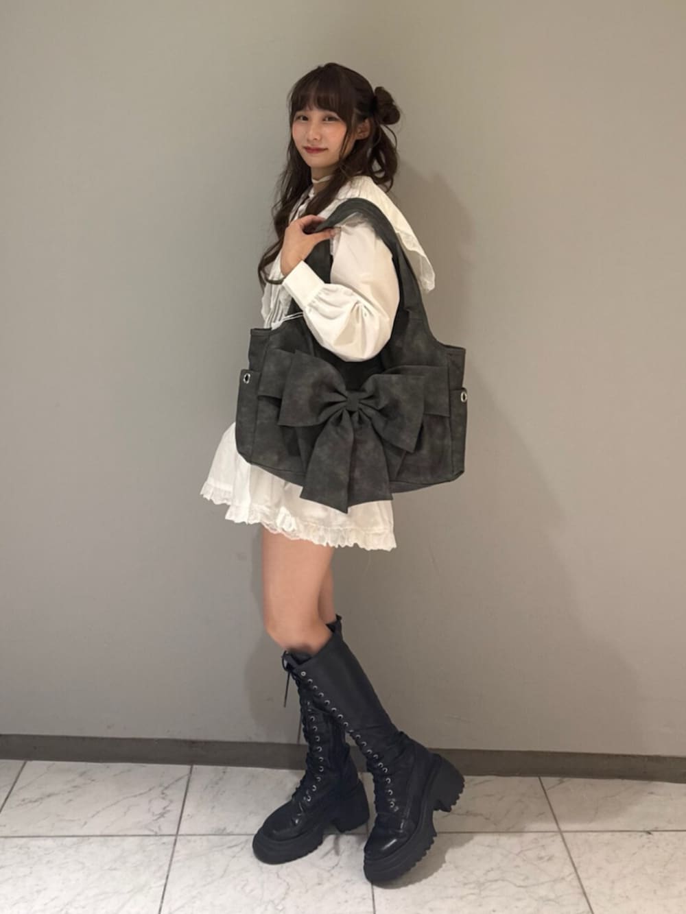 グレー系のトートバッグ、ブラック系のブーツ、ホワイト系のワンピースを着用したレディースの夏コーディネートの2枚目の写真