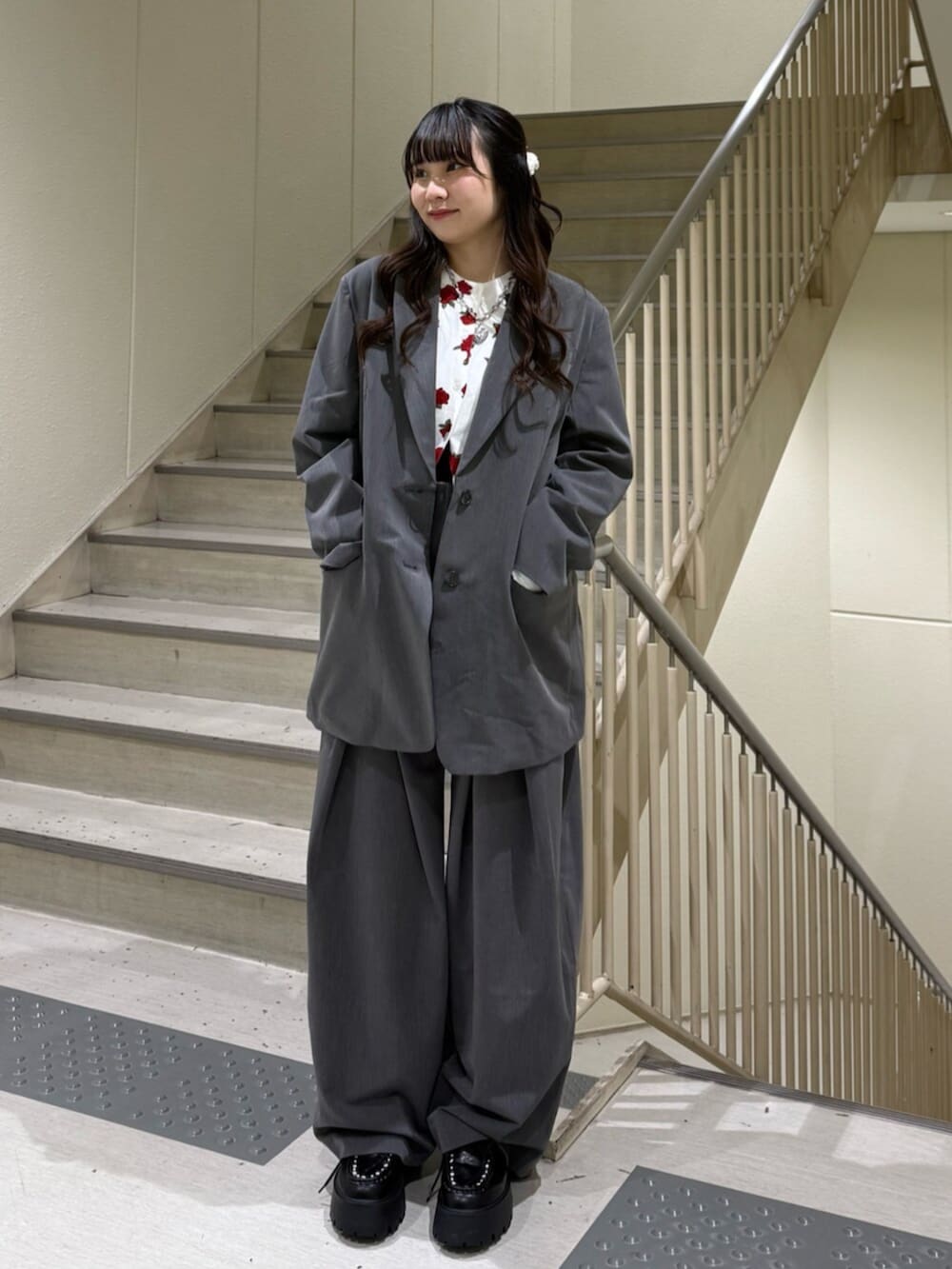 グレー系のスラックス、グレー系のテーラードジャケット、ホワイト系のカーディガン/ボレロを着用したレディースの冬コーディネートの3枚目の写真