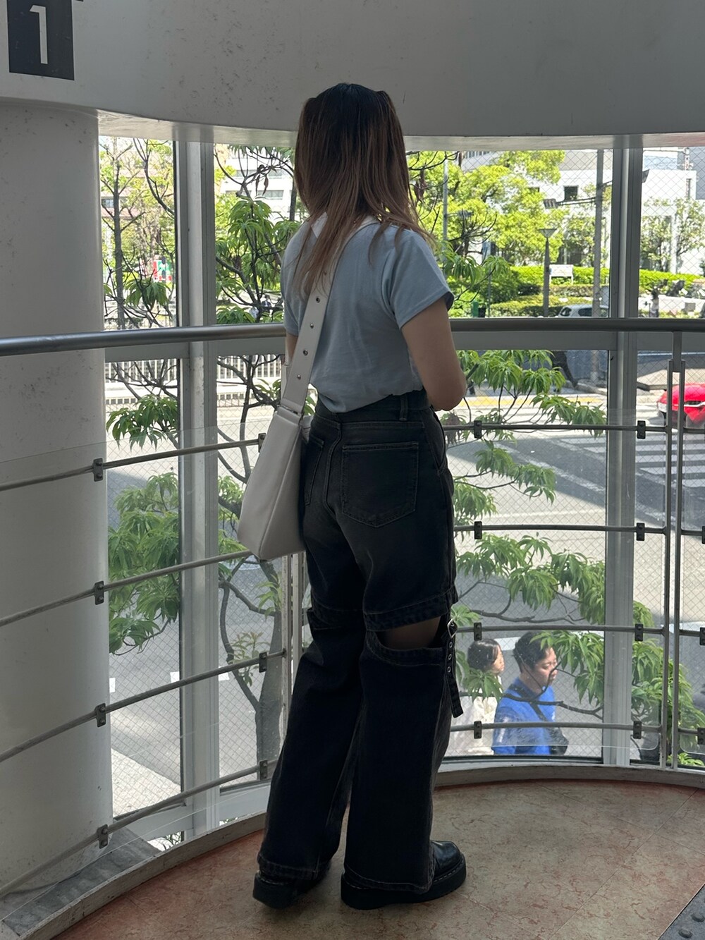 ブラック系のデニムパンツ、ホワイト系のショルダーバッグ、ブルー系のTシャツ/カットソーを着用したレディースの春コーディネートの2枚目の写真