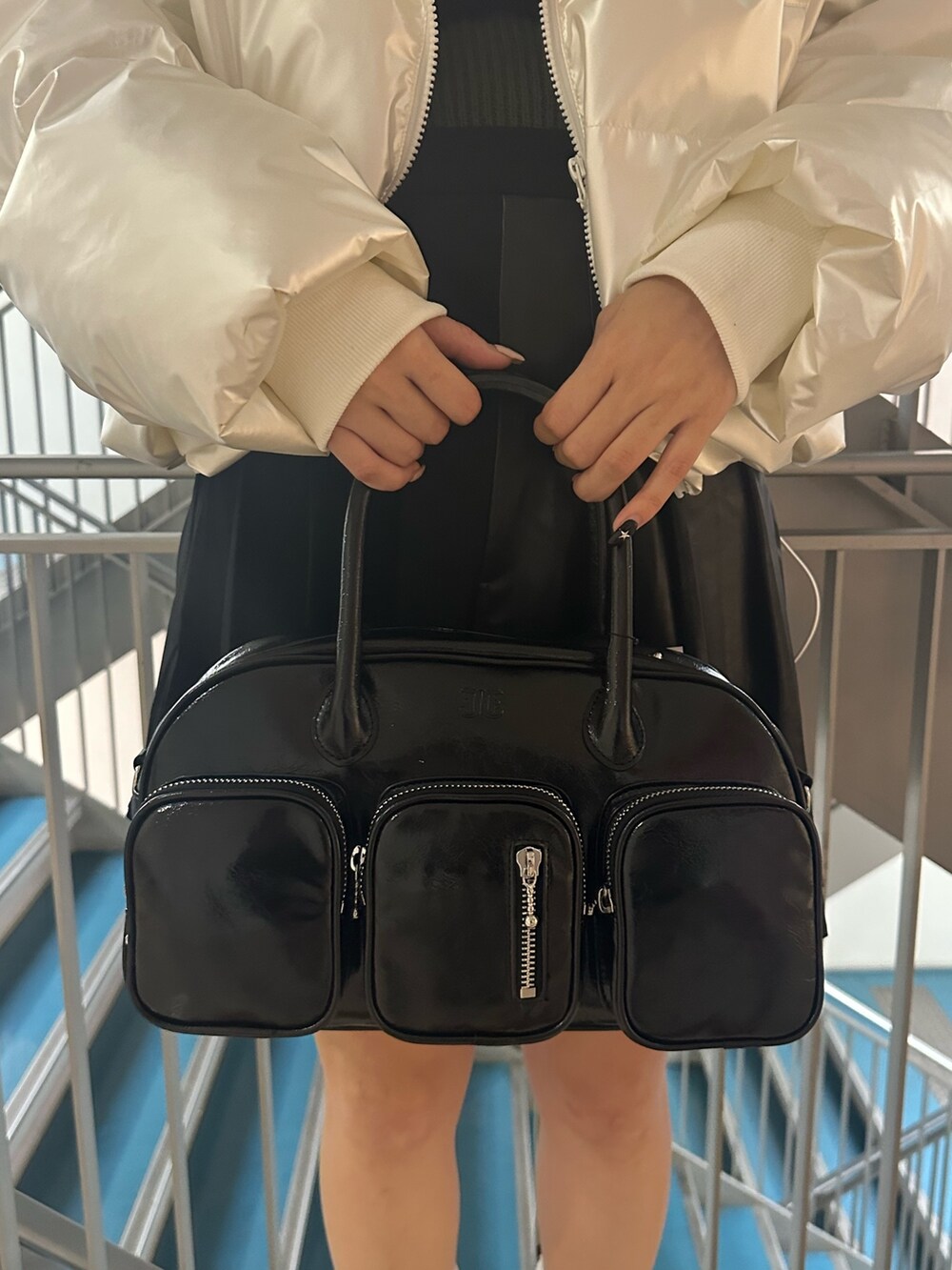 ブラック系のボストンバッグ、ホワイト系のダウンジャケット/コート、グリーン系のニット/セーターを着用したレディースの冬コーディネートの6枚目の写真