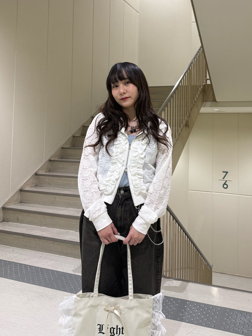 ホワイト系のパーカー、ブラック系のデニムパンツ、ホワイト系のトートバッグを着用したレディースの春コーディネートの8枚目の写真